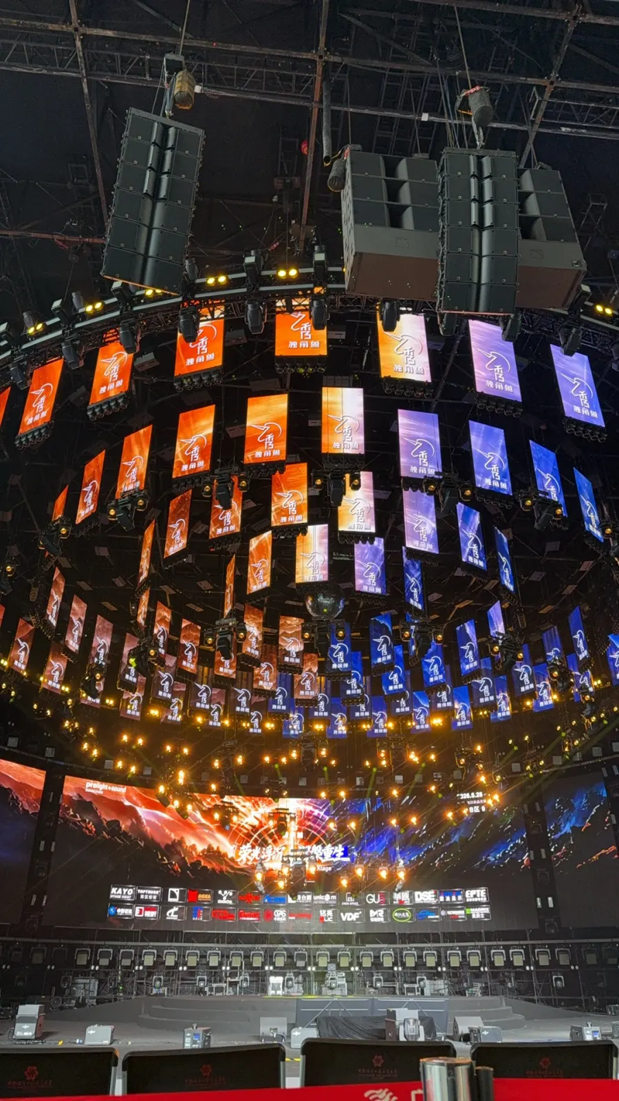 Large-format curved LED display and line-array speaker rig above a stadium stage